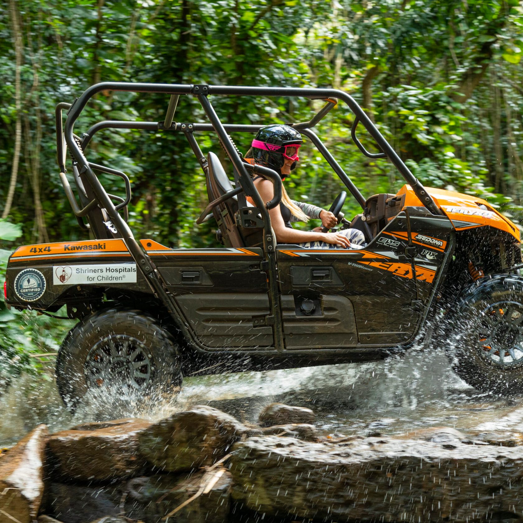 Girls driving a UTV through a puddle in the Hawaiian Rainforest