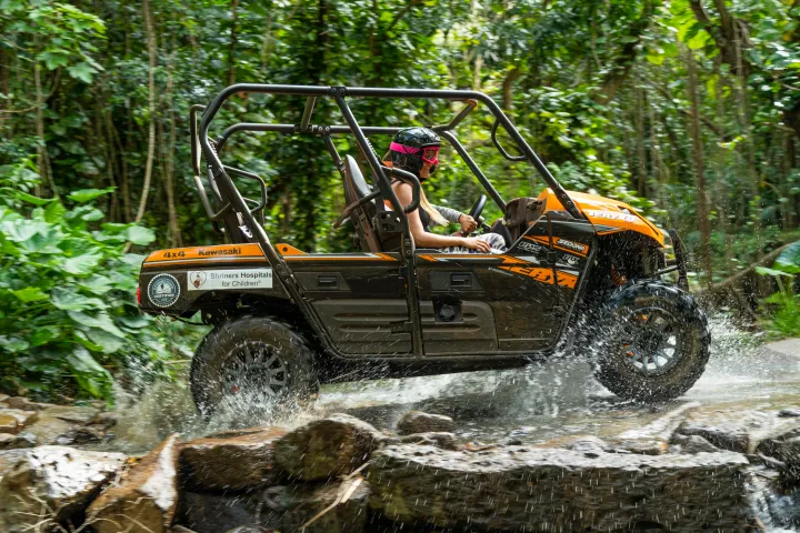 Girls driving a UTV through a puddle in the Hawaiian Rainforest