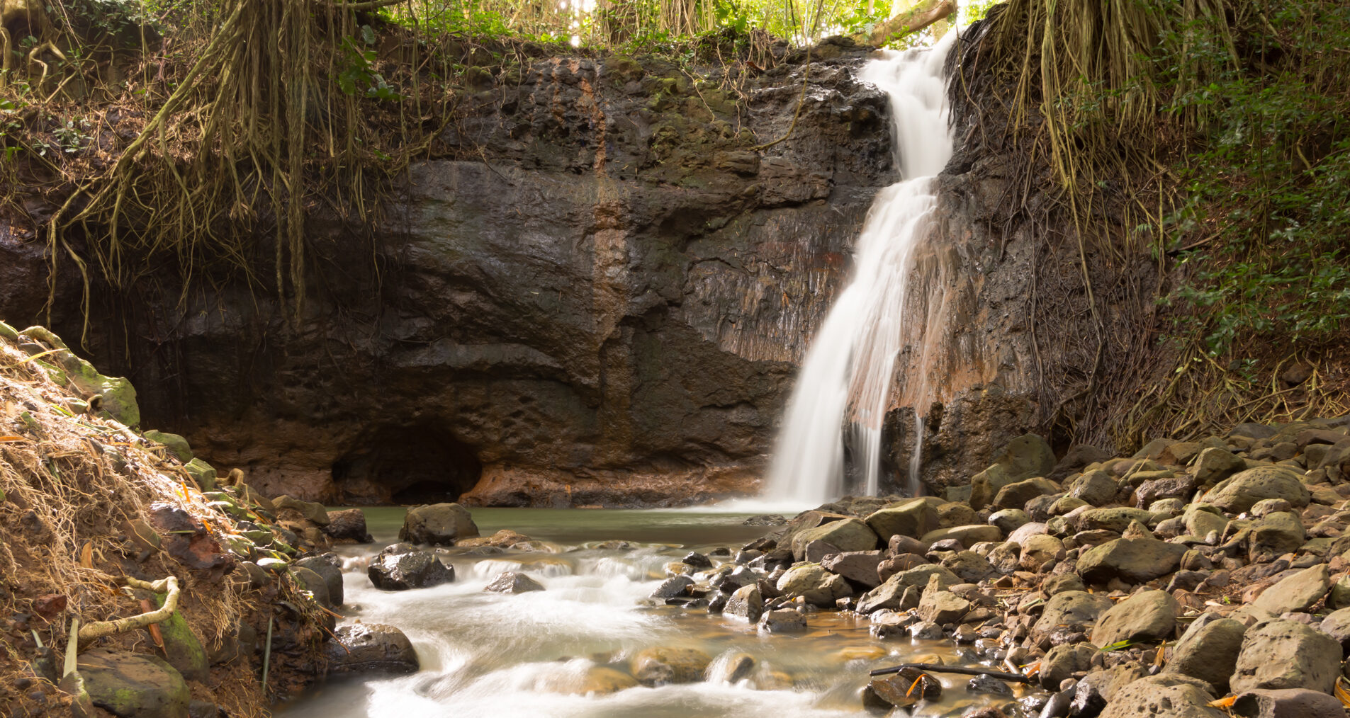 Waterfall surrounded by rock and tropical greenery at Kipu Ranch
